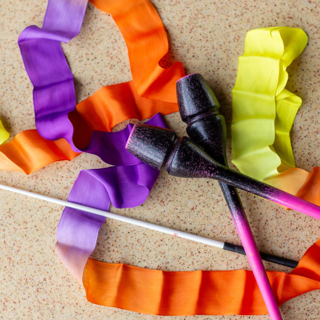 Colorful ribbon and Rhythmic gymnastics clubs on a textured surface