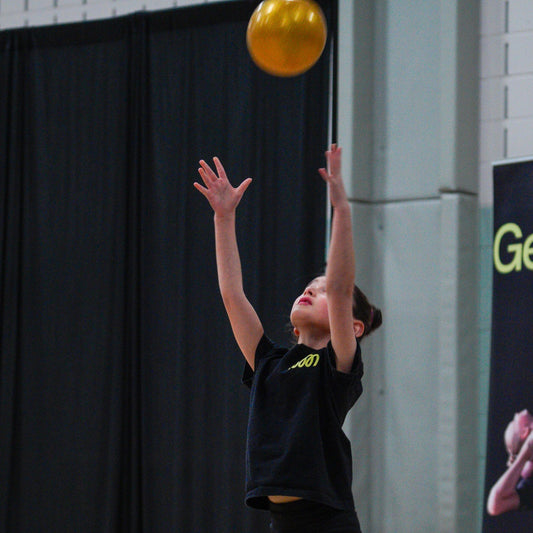 gymnast throwing a golden RG ball in the air