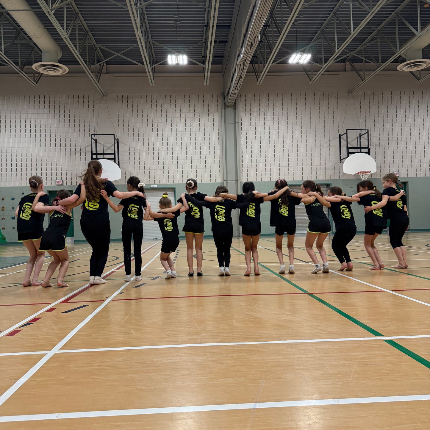 Group of gymnasts in black Gemmez shirts in a gymnasium