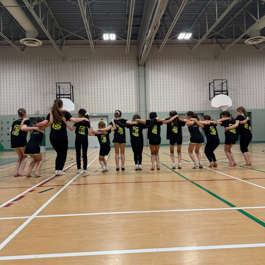 Group of gymnasts in black Gemmez shirts in a gymnasium