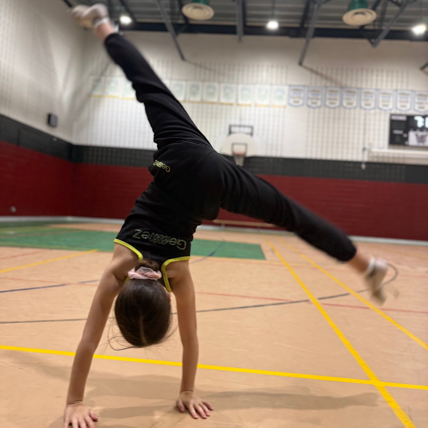 Gymnast in Cartwheel showcasing the back of track pants of the Gemmez brand