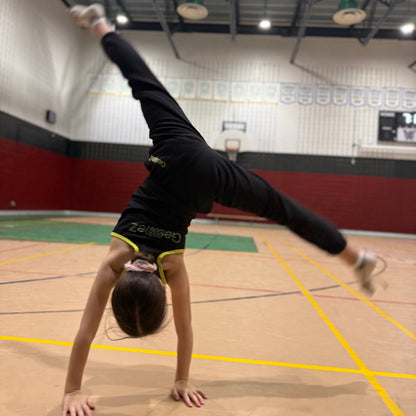 Gymnast in Cartwheel showcasing the back of track pants of the Gemmez brand