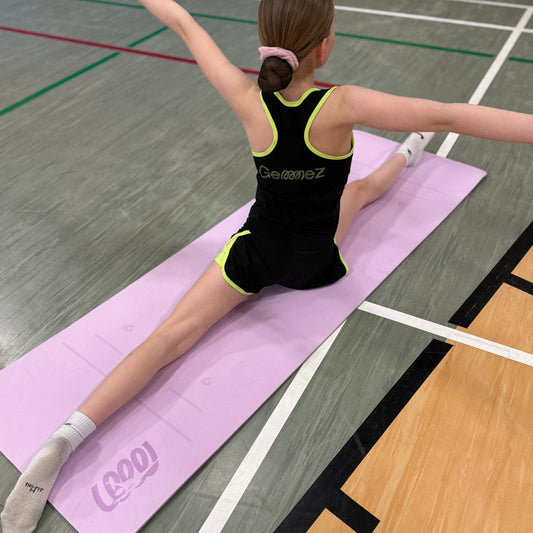 Gymnast on Gemmez branded purple yoga Mat sitting in a split showcasing the back of Gemmez branded tank top