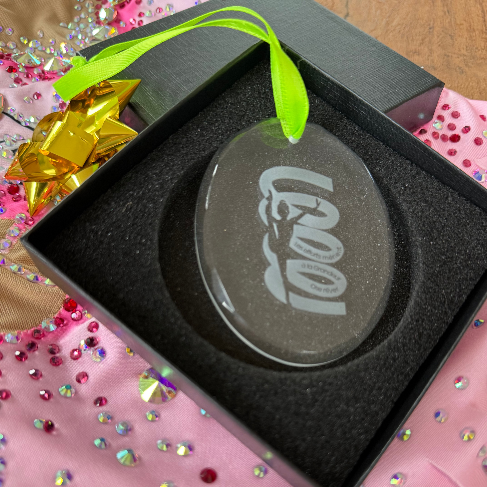 Decorative ornament with engraved design in a black box on a pink leotard.