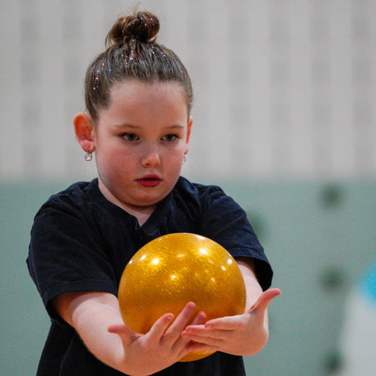 Rhythmic gymnast holding gold ball after roll