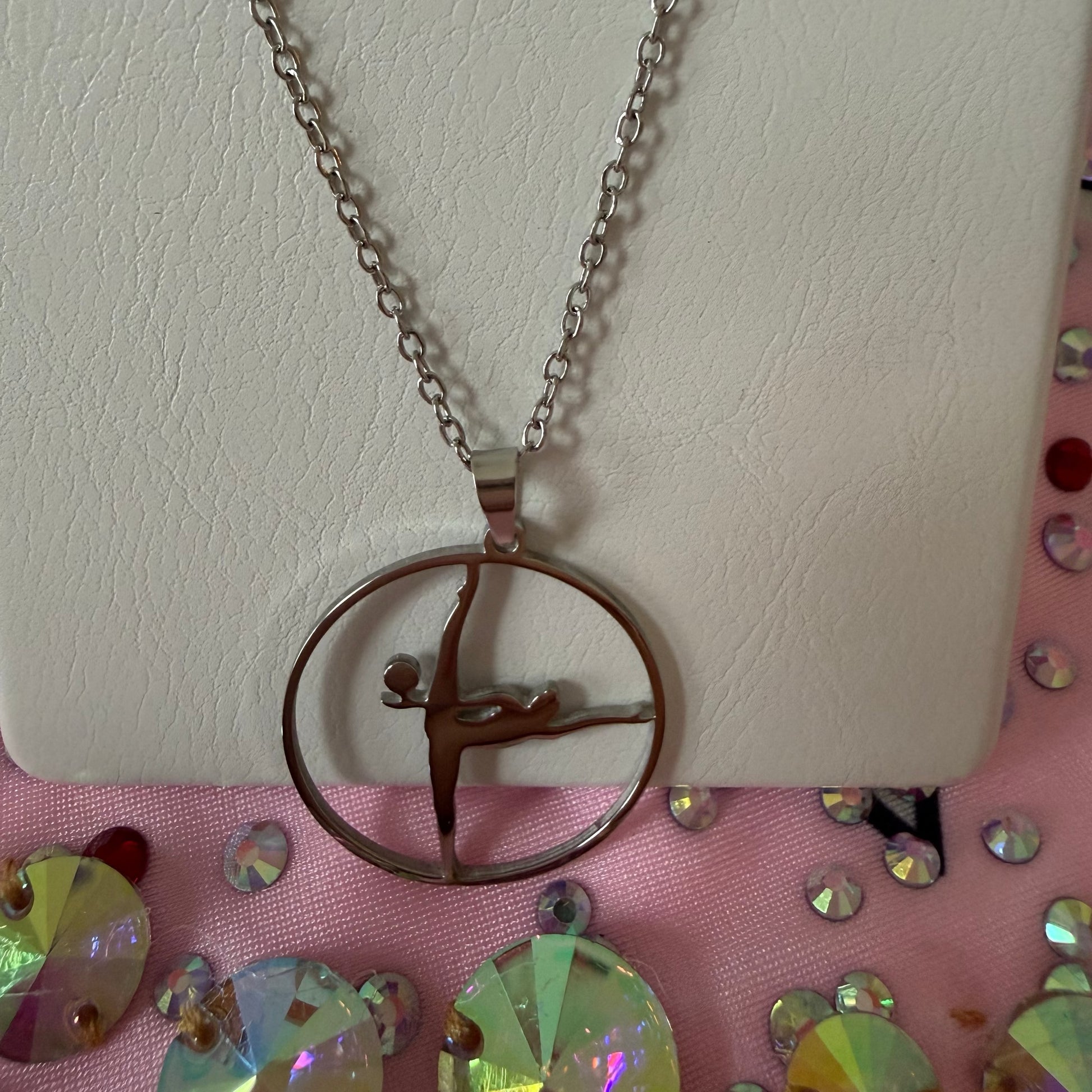 Necklace with a gymnast pendant on a white mirror with a colorful background
