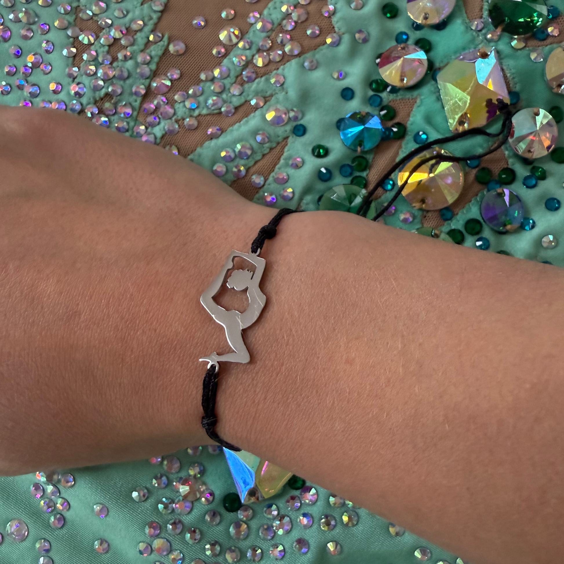 Bracelet with a unique gymnast design worn on a wrist against a mint leotard background.