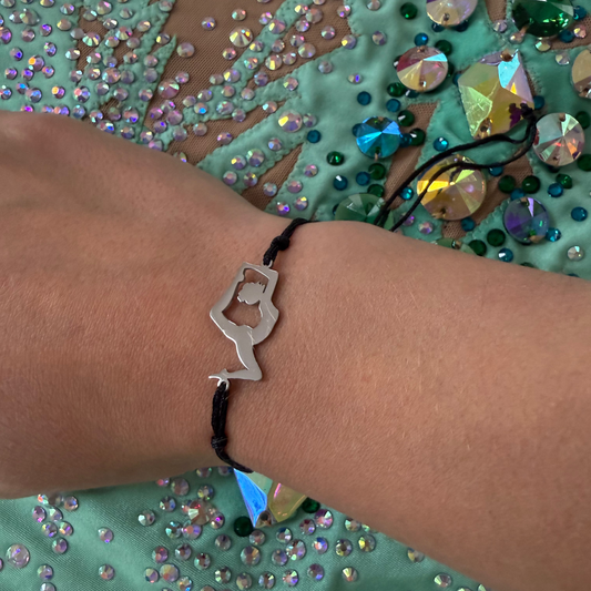Bracelet with a unique gymnast design worn on a wrist against a mint leotard background.