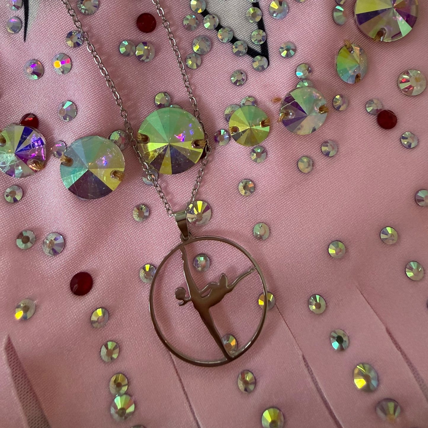 Necklace with a dancing figure pendant on a pink leotard background with rhinestones 