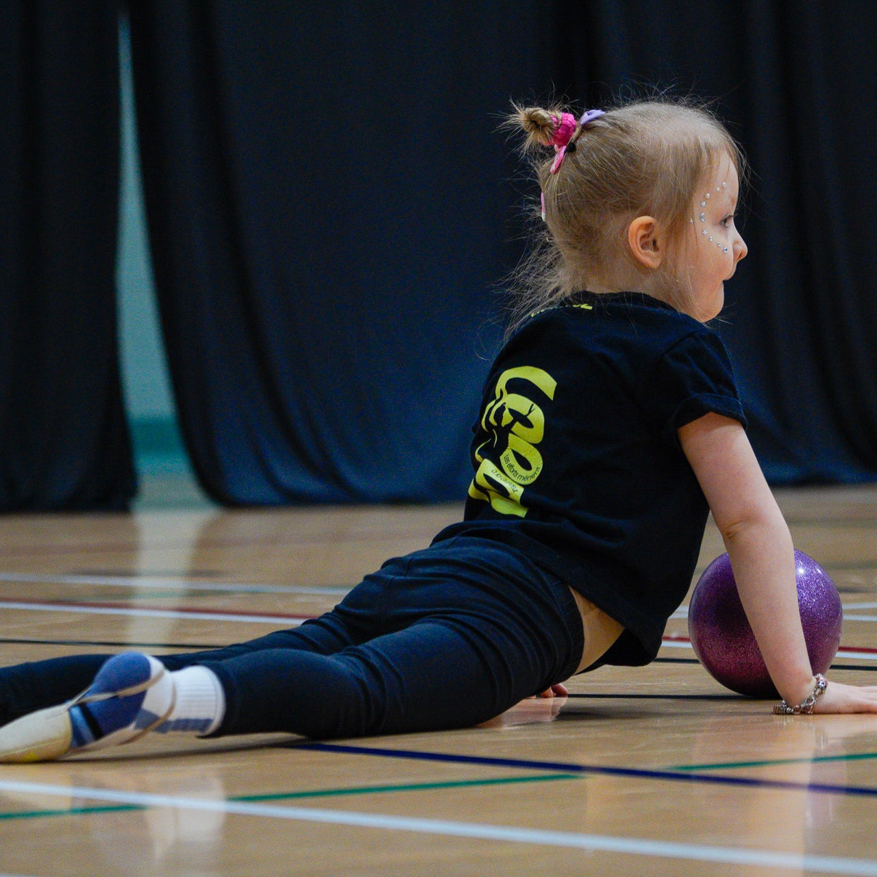 Young gymnast stretching with ball in cobra