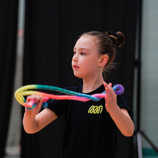 Young gymnast working skill with folded rope