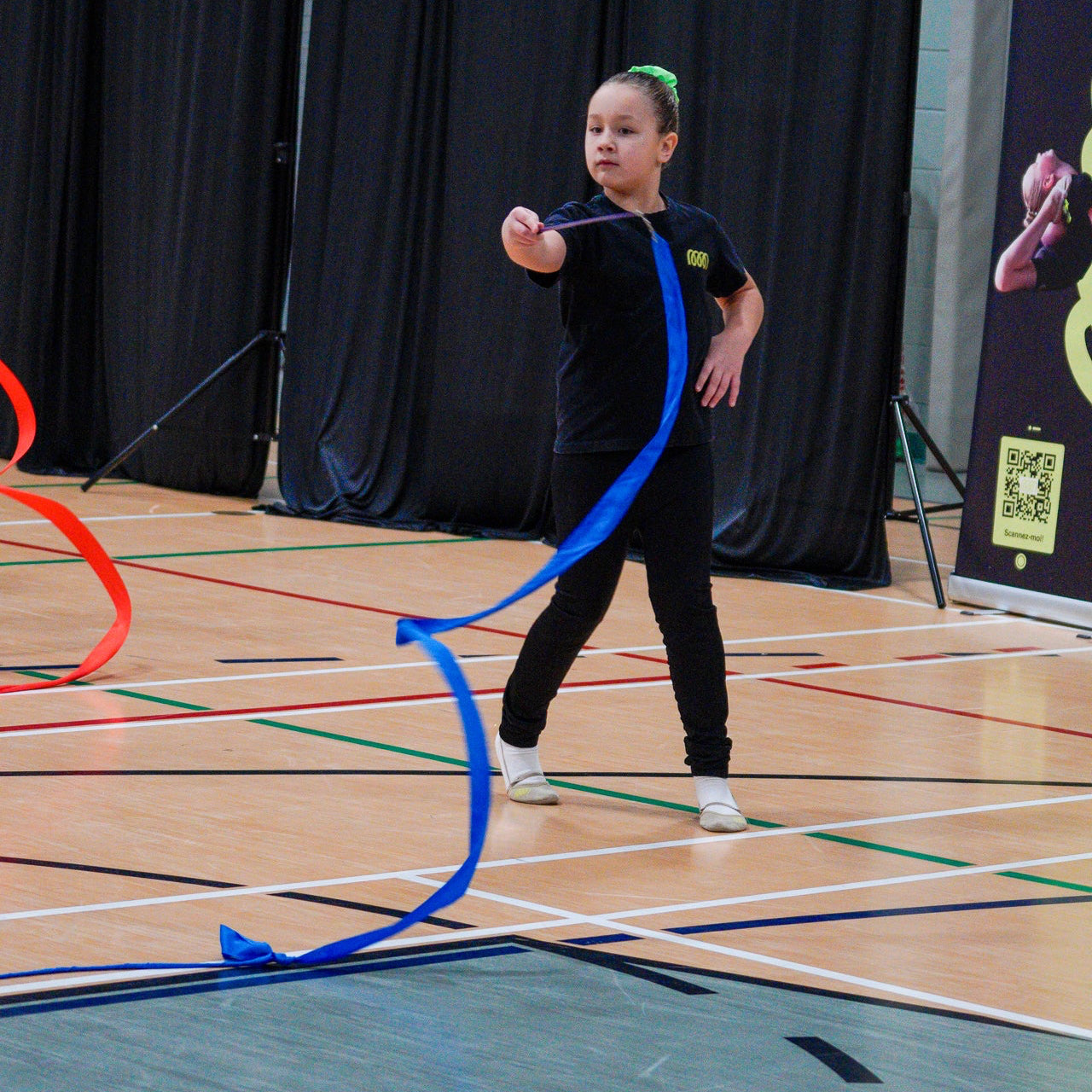 Young gymnast creating spirals with blue rayon ribbon