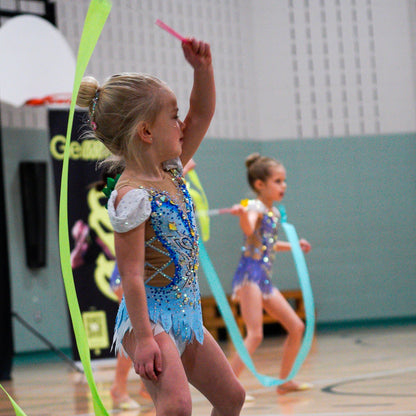 Young rhythmic gymnasts in leotards twisting ribbons