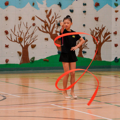 gymnast creating spirals with red rayon ribbon wearing the Gemmez brand t shirt
