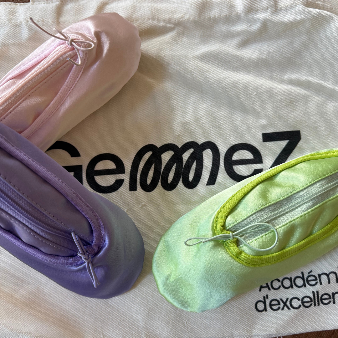 Three pairs of ballet shoes in pink, purple, and green on a bag with 'GemmeZ' branding.